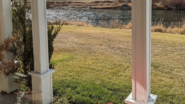 Un porche cubierto con vistas a un lago y colinas.