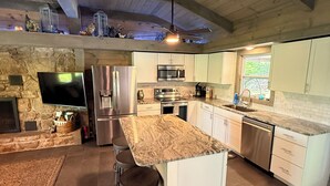Una cocina amplia con una isla grande, electrodomésticos integrados y una pared de acento de piedra.
