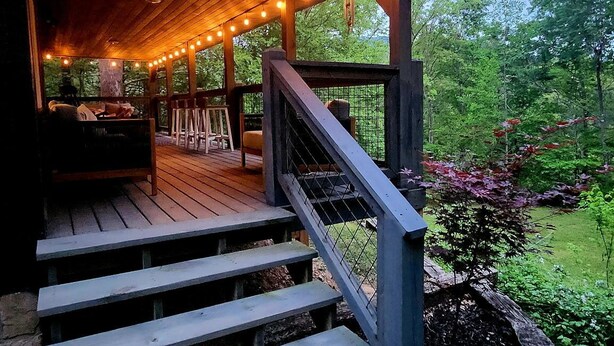 Una terraza de madera con mobiliario exterior y una escalera que lleva a un espacio cubierto.