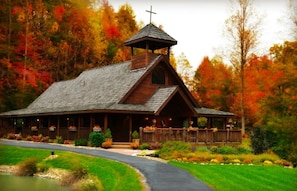 Une église en bois surmontée d’une croix, entourée d’un feuillage d’automne.