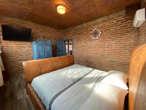 A room with a wooden bed, brick walls, and a mounted flat-screen TV. - 5 de Mayo Boutique Loft (Tijuana)