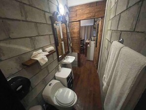 A narrow bathroom with a wooden accent wall, a white sink, a toilet, and a towel rack. - 5 de Mayo Boutique Loft (Tijuana)