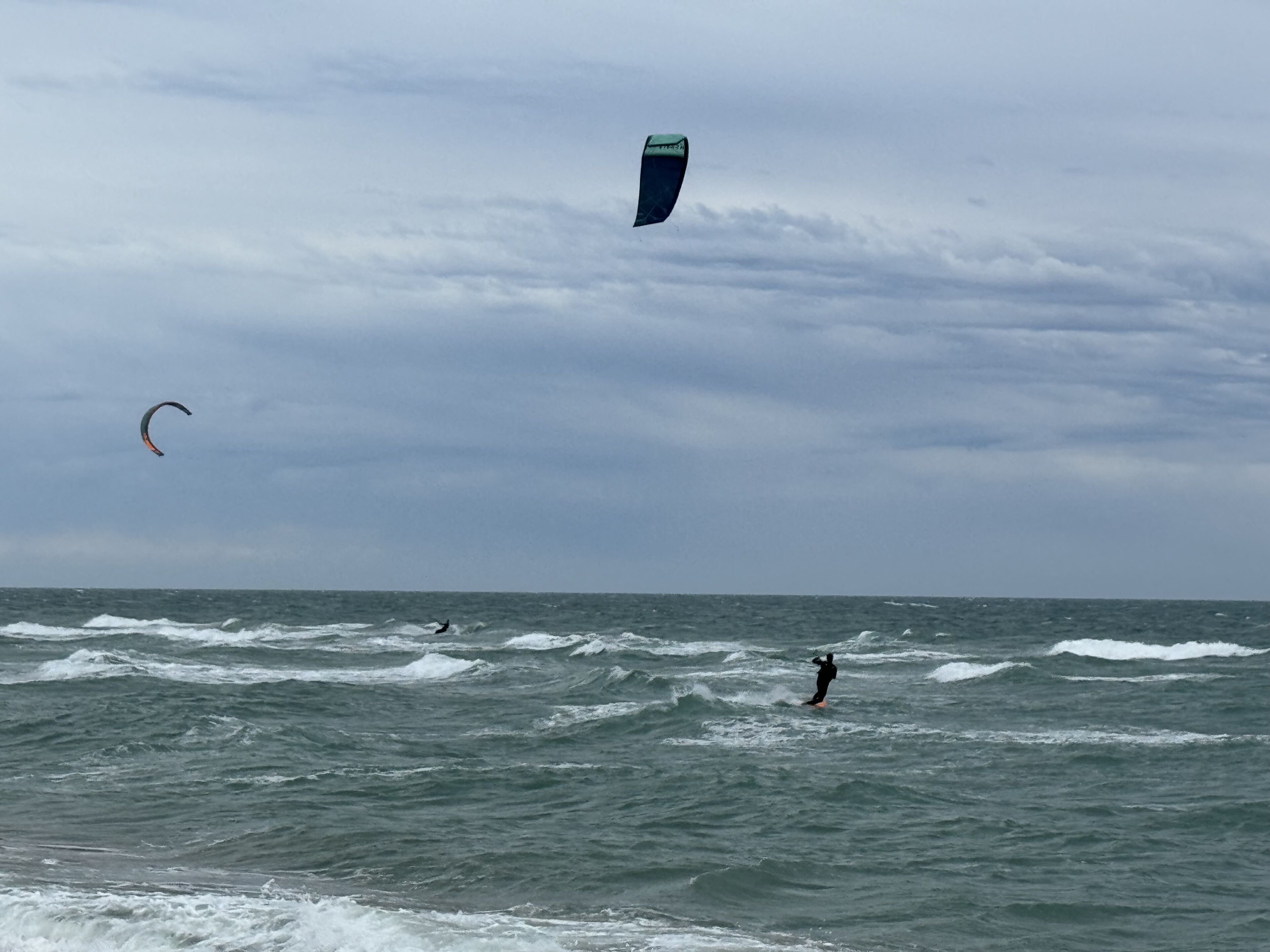 Una playa con olas y una persona practicando surf.