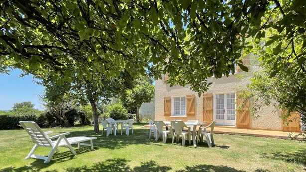 A patio area with outdoor seating and a stone building in the background. - Maison Puyoo - Theze (THEZE)