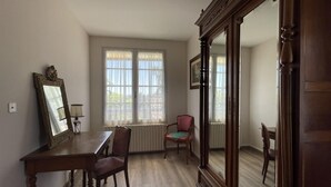 A room with a wooden dining table, two chairs, a large mirror, and a window with curtains. - Maison Puyoo - Theze (THEZE)