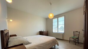 A bedroom with a bed, dresser, chair, and a window with a view. - Maison Puyoo - Theze (THEZE)