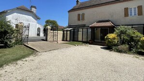 A residential property with a gravel driveway, a gated entrance, and a covered patio area. - Maison Puyoo - Theze (THEZE)