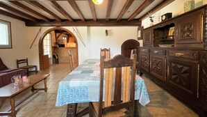 Un comedor rústico con una mesa y sillas de madera, un mantel estampado y un armario de madera con adornos decorativos.