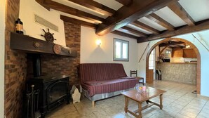 Una sala de estar acogedora con vigas de madera a la vista, una chimenea de ladrillo, un sofá a rayas y una mesa de centro de madera.