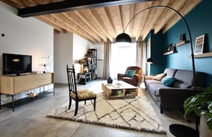 A modern living room with a wooden ceiling, a television on a wooden cabinet, a sofa, a coffee table, and a chair. - Maison Mado-lily - Bidos (BIDOS)