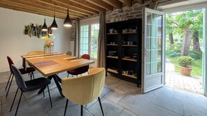 A dining area with a wooden table and chairs, pendant lights, and a view of a garden through a glass door. - Maison Mado-lily - Bidos (BIDOS)