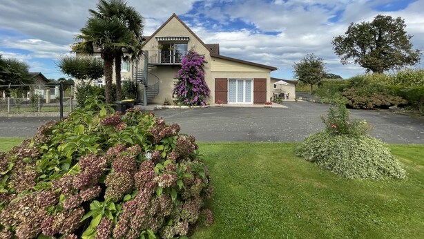 A two-story house with a balcony, surrounded by a well-maintained lawn and various plants. - CHEZ LABAT 2 - ESPOEY (ESPOEY)