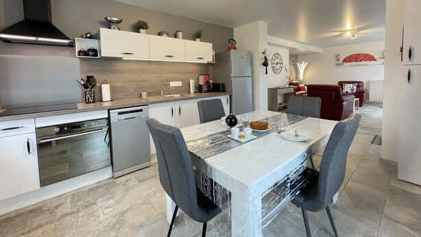 A modern kitchen with white cabinetry, a built-in oven, and a dining area with a marble table and grey chairs. - Uharte Beherea - Souraide (SOURAIDE)