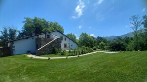 Una casa con escaleras de piedra, fachada blanca y césped verde.
