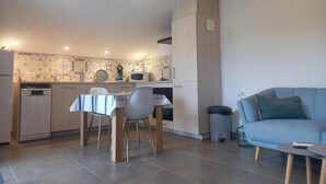 Una cocina moderna con comedor, un sofá azul y una pequeña mesa.