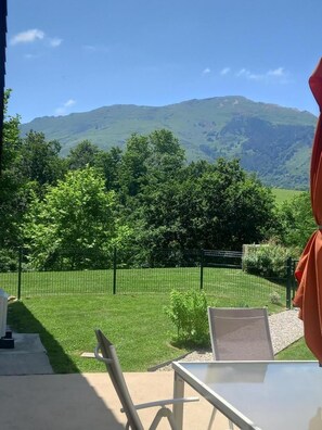 A patio with a table and chairs, a view of a green landscape with trees and a mountain in the background. - Heia - Sare - Gîte (SARE)