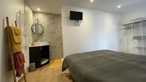Una camera da letto con un letto, un comodino, uno specchio, una TV a parete e un armadio a muro.
