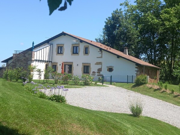 A two-story building with a stone facade, a red-tiled roof, and a gravel driveway leading to the entrance. - Heia - Sare - Gîte (SARE)