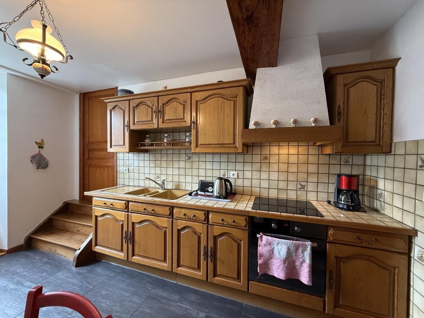 Une cuisine avec des meubles de rangement en bois, un évier, une cuisinière et une machine à café.