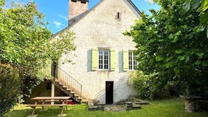 Een stenen huis met een trap, een deur en een kleine tuin met een picknicktafel.