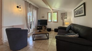 A living room with a sofa, armchair, TV, and a window with curtains. - Xirimola BI - Saint-pee-sur-nivelle (SAINT-PEE-SUR-NIVELLE)