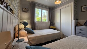 A bedroom with two beds, a window with curtains, a desk with a lamp, and a dresser. - Xirimola BI - Saint-pee-sur-nivelle (SAINT-PEE-SUR-NIVELLE)