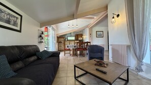A living room with a sofa, a coffee table, and a kitchen in the background. - Xirimola BI - Saint-pee-sur-nivelle (SAINT-PEE-SUR-NIVELLE)