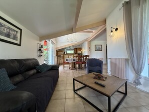 A living room with a sofa, a coffee table, and a kitchen in the background.