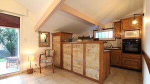 A kitchen with wooden cabinets, a built-in island, and a microwave. - Xirimola BI - Saint-pee-sur-nivelle (SAINT-PEE-SUR-NIVELLE)