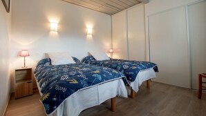 Een slaapkamer met twee bedden, een houten vloer en een kledingkast.