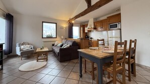 Un salon confortable avec un canapé, une petite table et une table à manger avec des chaises. Il y a également un coin cuisine avec des meubles en bois et des appareils électroménagers.