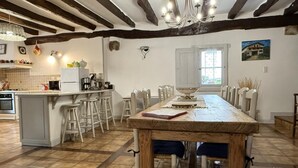 A spacious kitchen with a large island, wooden beams, and a dining area with white chairs. - BORTABARATZEA 1 - SAINT-PEE-SUR-NIVELLE (SAINT-PEE-SUR-NIVELLE)
