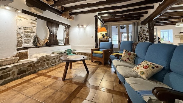 A rustic living room with exposed wooden beams, a stone wall, and a blue sofa. - BORTABARATZEA 1 - SAINT-PEE-SUR-NIVELLE (SAINT-PEE-SUR-NIVELLE)
