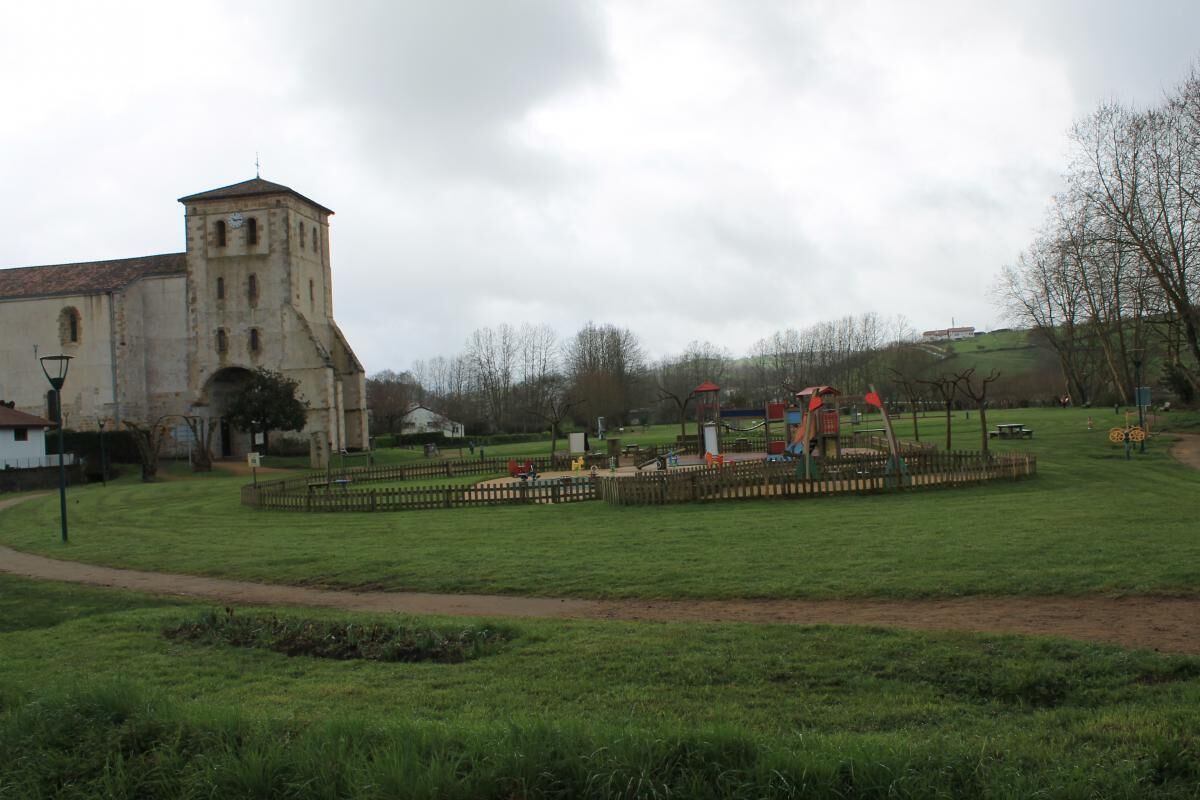 A historic building with a bell tower, surrounded by a grassy area with playground equipment.
