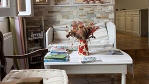 A cozy living room with a white sofa, a coffee table with books and a vase, and a fireplace with a stone backsplash. - BORTABARATZEA 1 - SAINT-PEE-SUR-NIVELLE (SAINT-PEE-SUR-NIVELLE)