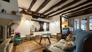 A cozy living room with exposed wooden beams, a stone fireplace, and a blue sofa. - BORTABARATZEA 1 - SAINT-PEE-SUR-NIVELLE (SAINT-PEE-SUR-NIVELLE)
