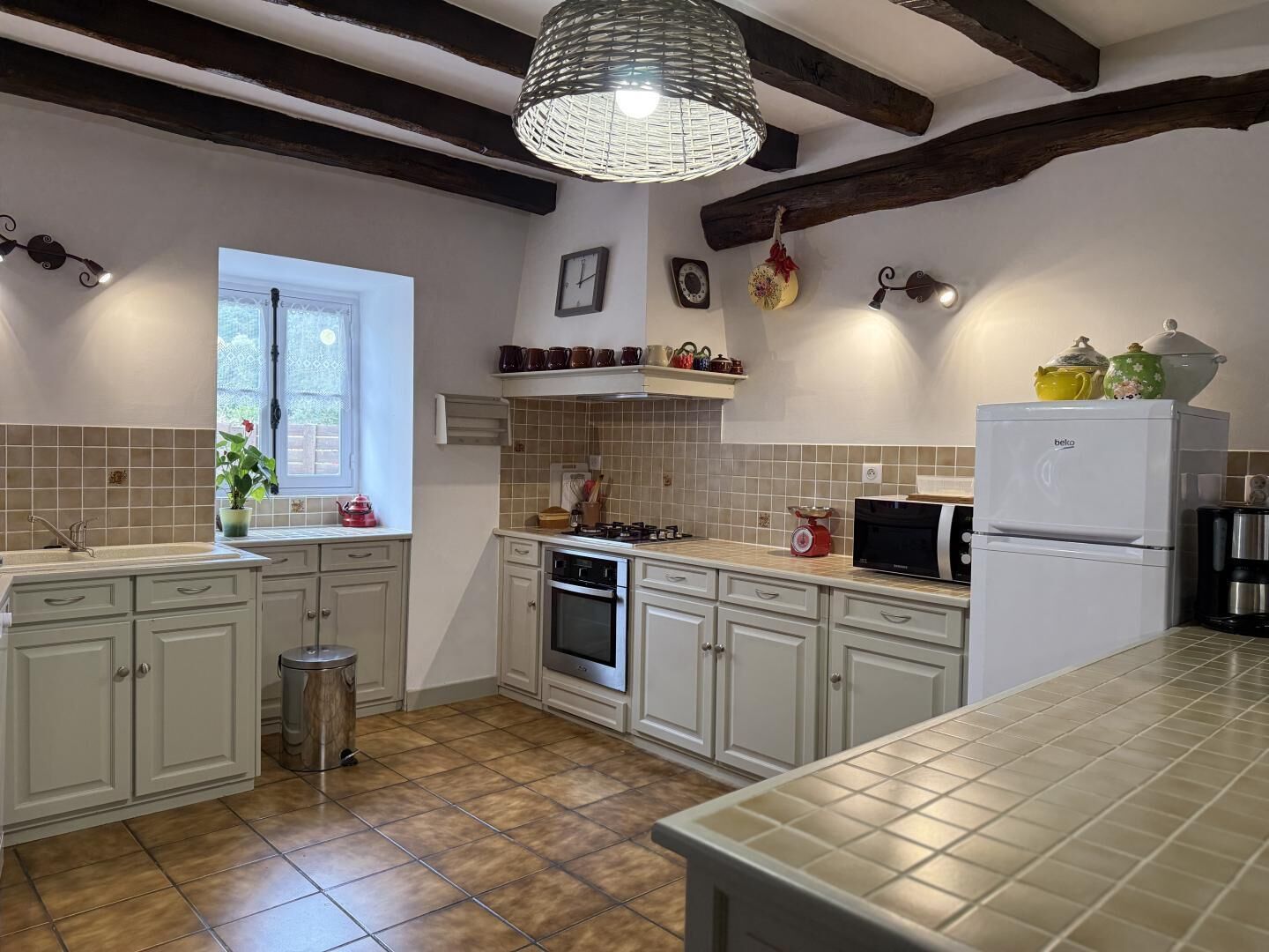 A kitchen with white cabinets, a stove, a microwave, and a refrigerator.