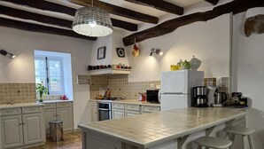 A kitchen with a large island, white cabinets, a hanging light fixture, and a window with a view. - BORTABARATZEA 1 - SAINT-PEE-SUR-NIVELLE (SAINT-PEE-SUR-NIVELLE)