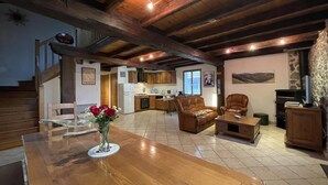 A spacious living area with a wooden dining table, leather sofas, and a kitchen in the background. - Haizalde - Saint-jean-le-vieux (SAINT-JEAN-LE-VIEUX)