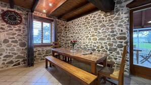 A rustic dining area with a stone wall, wooden ceiling beams, and a wooden table with benches. - Haizalde - Saint-jean-le-vieux (SAINT-JEAN-LE-VIEUX)