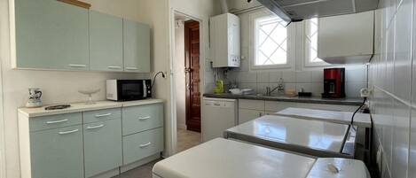 A compact kitchen with a washing machine, a microwave, and a coffee maker.