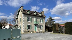 A two-story building with a gravel driveway and a green metal fence. - LACAZE-BUSQUET - GELOS (GELOS)