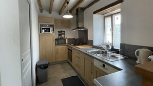 Una cocina compacta con armarios de madera, microondas, estufa a gas y un lavamanos.