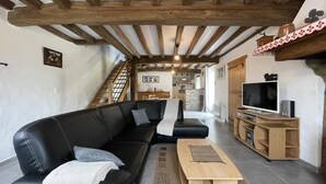 Una sala de estar con un sofá de cuero negro, una mesa de centro de madera y un mueble bajo para televisión con una pantalla plana.