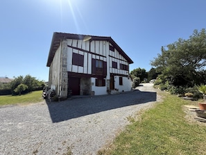 Um edifício de dois andares com fachada de pedra, entrada com calçamento e gramado bem cuidado.