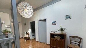 A spacious hallway with a tiled floor, a wooden cabinet with a bowl and plant, and a chair. - Haizteia - Saint-pee-sur-nivelle (SAINT-PEE-SUR-NIVELLE)