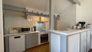 A modern kitchen with white cabinetry, a microwave, a stove, and a coffee maker. - Haizteia - Saint-pee-sur-nivelle (SAINT-PEE-SUR-NIVELLE)