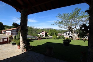 A stone-paved patio with a view of a rural landscape, including houses and a mountain in the distance.