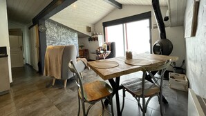 A cozy kitchen with a large stove, wooden table, and chairs. - Xokoan - Sare - Gîte (SARE)