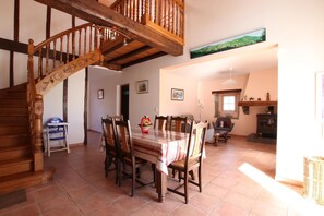A dining area with a wooden staircase, a dining table with chairs, and a fireplace. - Ur-ondoa - Larceveau (LARCEVEAU)